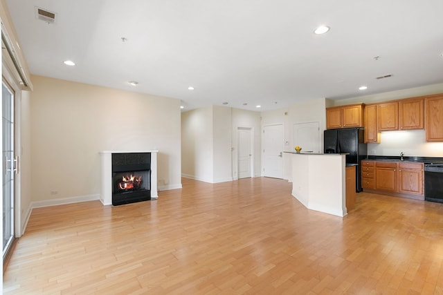 kitchen with recessed lighting, a fireplace with flush hearth, open floor plan, light wood-type flooring, and black appliances