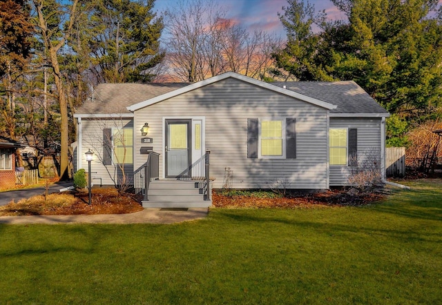 view of front of home with a lawn and a shingled roof