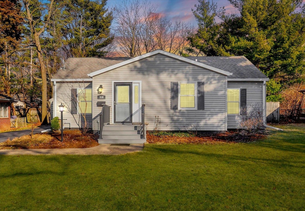 view of front of home with a lawn and roof with shingles