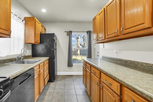 kitchen with light tile patterned floors, baseboards, a sink, black appliances, and brown cabinets