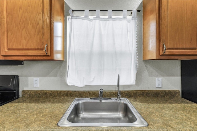 kitchen with dark countertops, brown cabinetry, and a sink