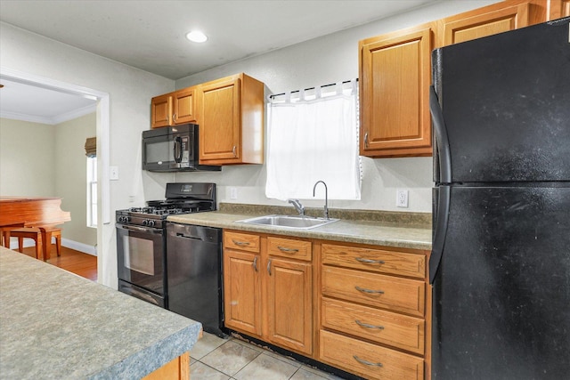 kitchen featuring crown molding, light tile patterned floors, brown cabinetry, black appliances, and a sink