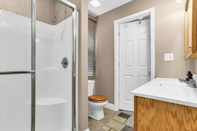 bathroom featuring vanity, toilet, baseboards, and a stall shower