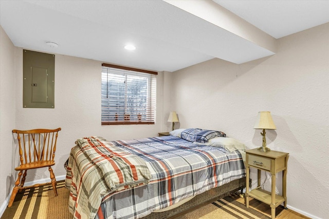 bedroom with electric panel, a textured wall, and baseboards