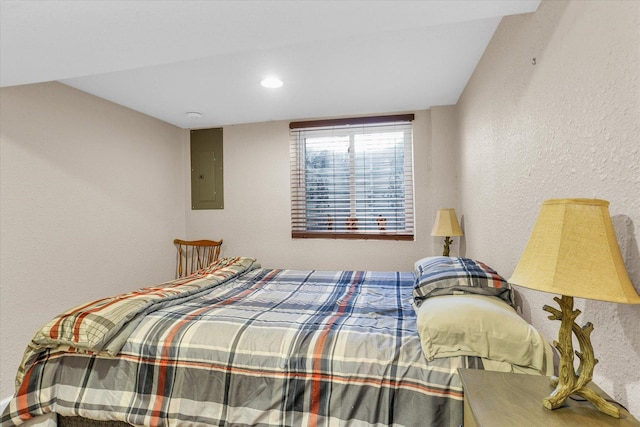 bedroom featuring electric panel and a textured wall