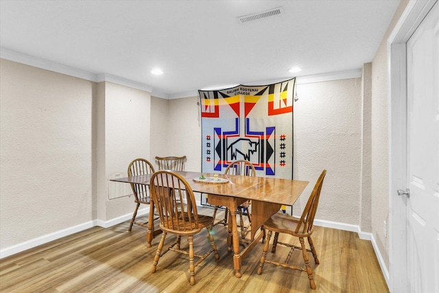 dining room featuring visible vents, ornamental molding, baseboards, and wood finished floors