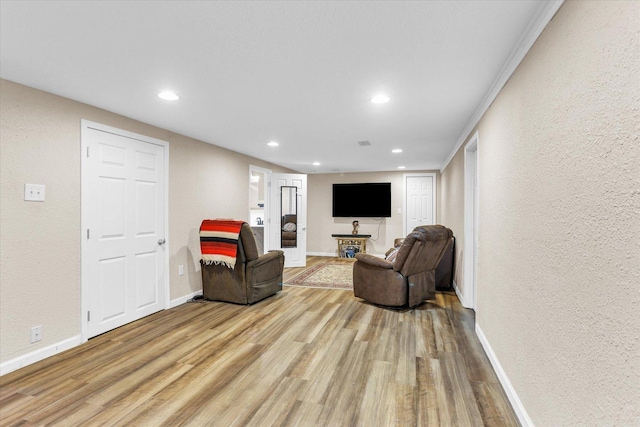 sitting room with a textured wall, recessed lighting, baseboards, and wood finished floors