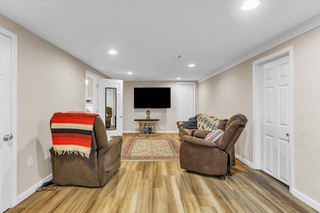 living room featuring visible vents, baseboards, ornamental molding, recessed lighting, and light wood-style flooring