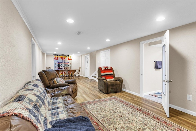 living room featuring visible vents, baseboards, wood finished floors, recessed lighting, and a textured wall