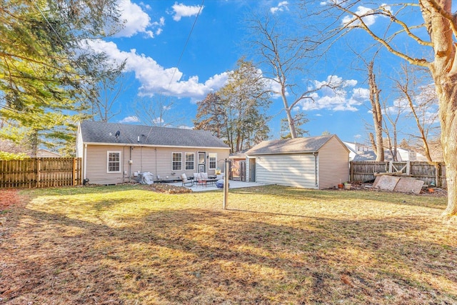 back of house featuring a fenced backyard, a lawn, an outdoor structure, and a patio