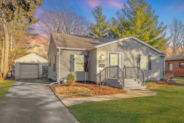 bungalow-style home with an outbuilding, a front yard, driveway, roof with shingles, and a garage