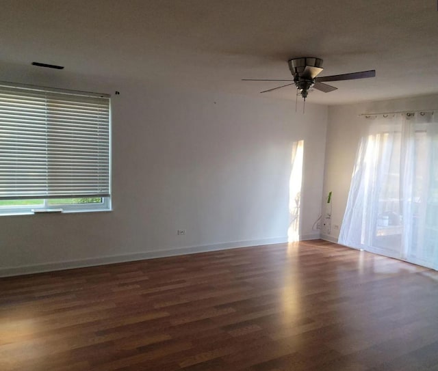 spare room with ceiling fan, wood finished floors, a wealth of natural light, and baseboards