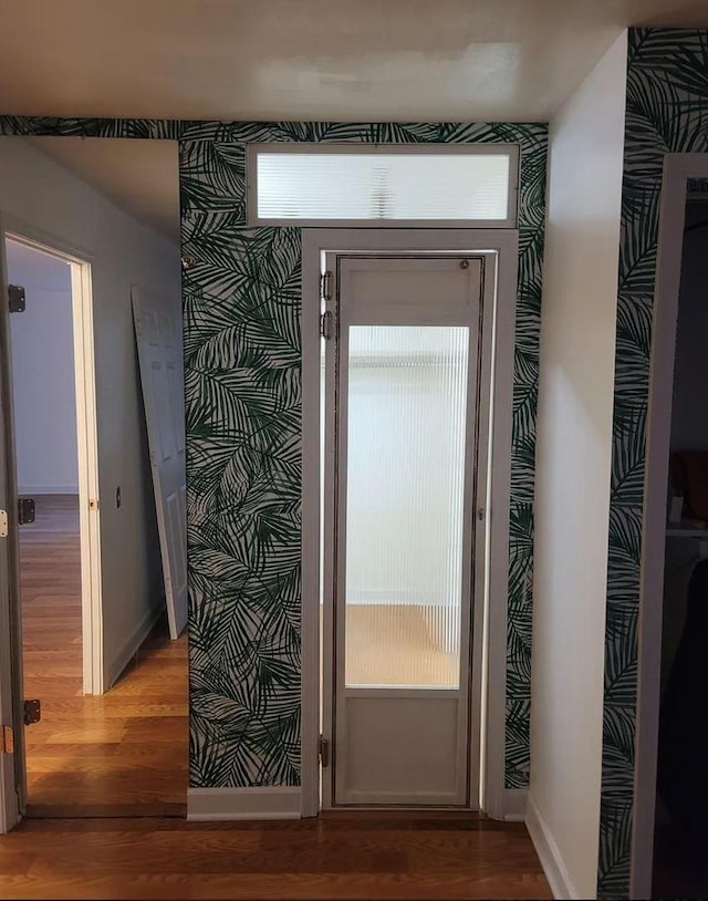 doorway to outside with a healthy amount of sunlight, wallpapered walls, baseboards, and wood finished floors