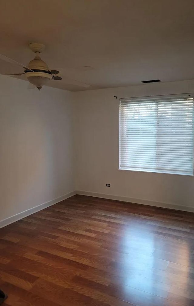 unfurnished room with dark wood finished floors, visible vents, and baseboards