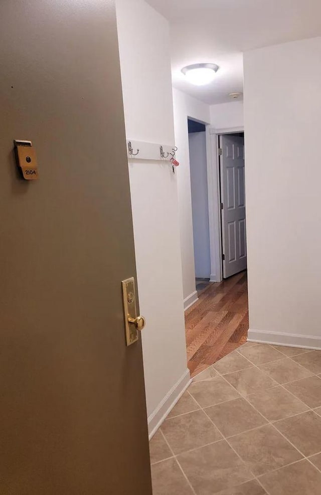 corridor with light tile patterned floors and baseboards