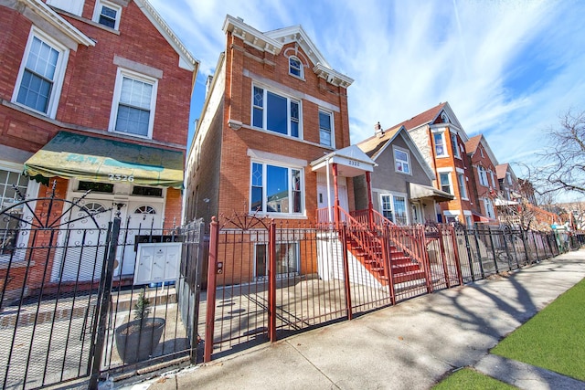 view of front facade featuring a fenced front yard, a residential view, and brick siding