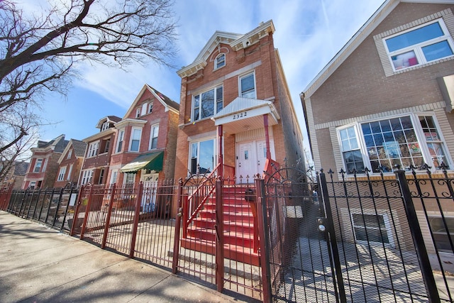 view of property featuring a fenced front yard, a gate, and brick siding