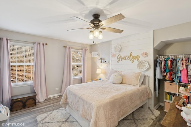 bedroom with ceiling fan, wood finished floors, and baseboards