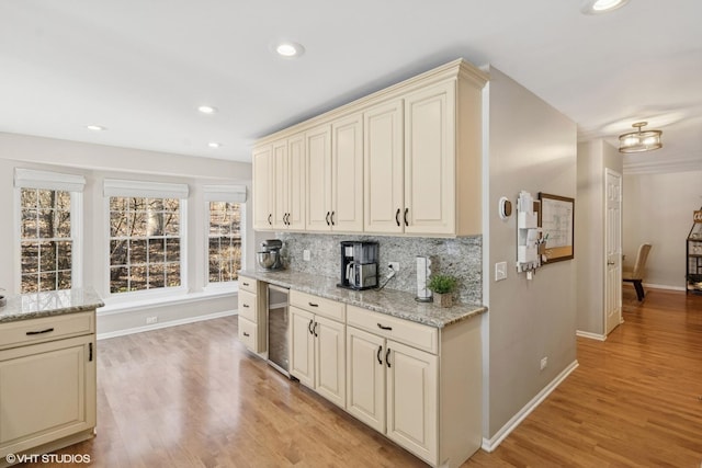 kitchen with beverage cooler, tasteful backsplash, baseboards, cream cabinetry, and light wood-type flooring