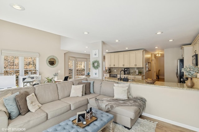 living room with baseboards, light wood-type flooring, and recessed lighting