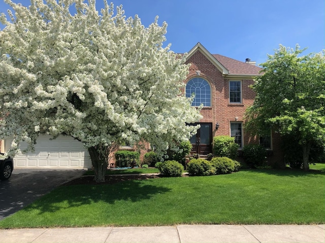 view of front of property featuring a front yard, brick siding, and driveway