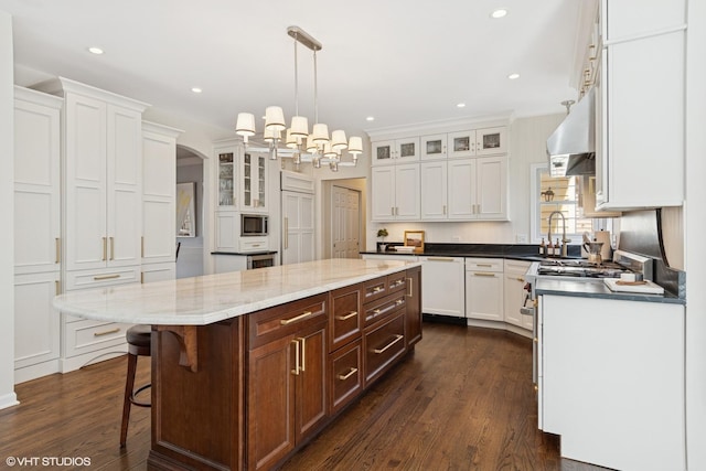 kitchen featuring white cabinets, a center island, under cabinet range hood, and stainless steel appliances