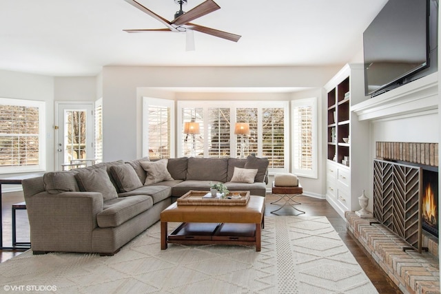 living room with a brick fireplace, wood finished floors, and a healthy amount of sunlight