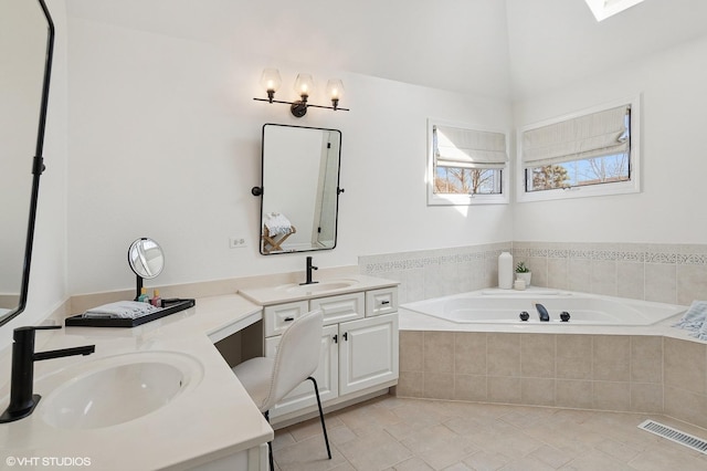 full bath featuring a sink, visible vents, two vanities, and a bath