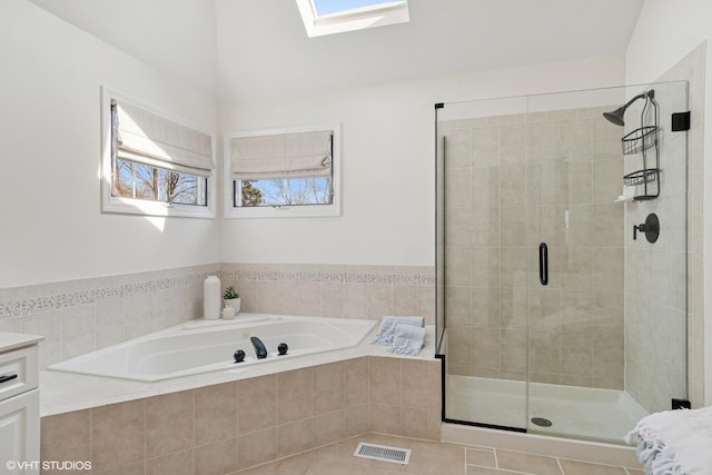 full bathroom with a bath, visible vents, a shower stall, and a skylight