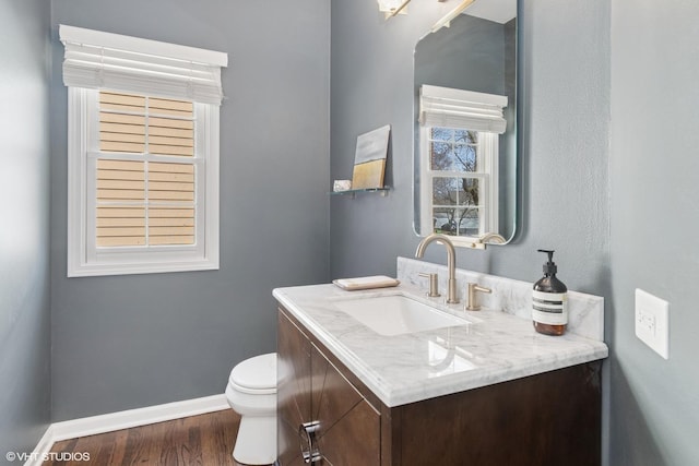 bathroom with toilet, vanity, baseboards, and wood finished floors