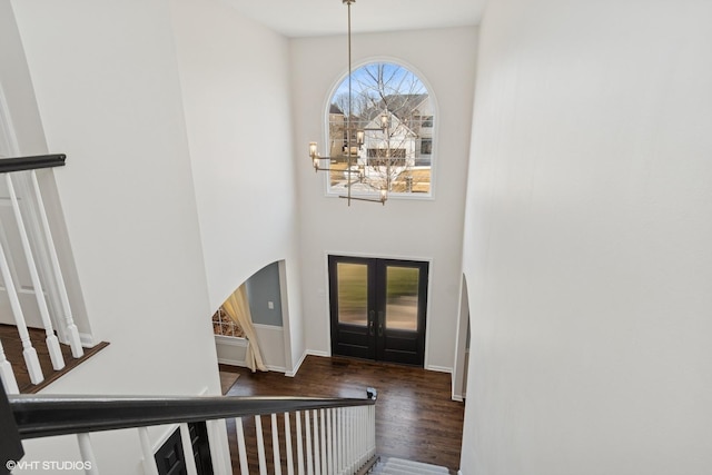 foyer entrance featuring a chandelier, stairs, baseboards, and wood finished floors