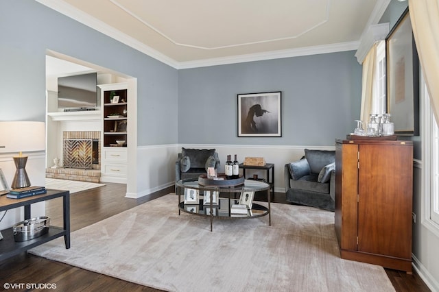 sitting room featuring crown molding, a brick fireplace, wood finished floors, and baseboards