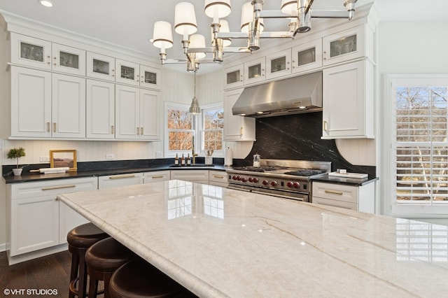 kitchen with decorative backsplash, range with two ovens, white cabinets, and under cabinet range hood