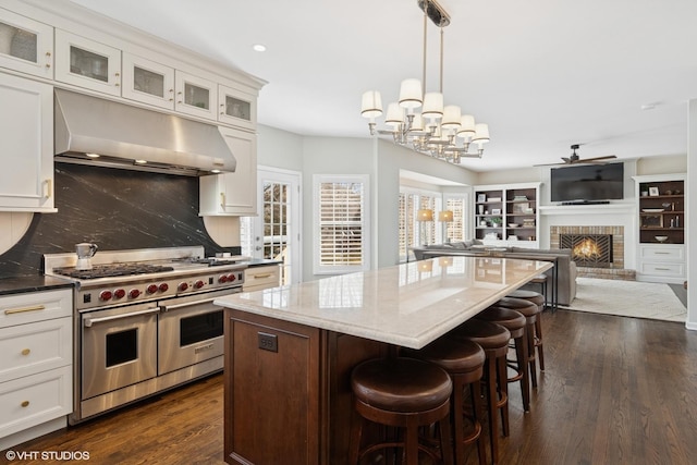 kitchen with white cabinetry, double oven range, under cabinet range hood, and a kitchen island