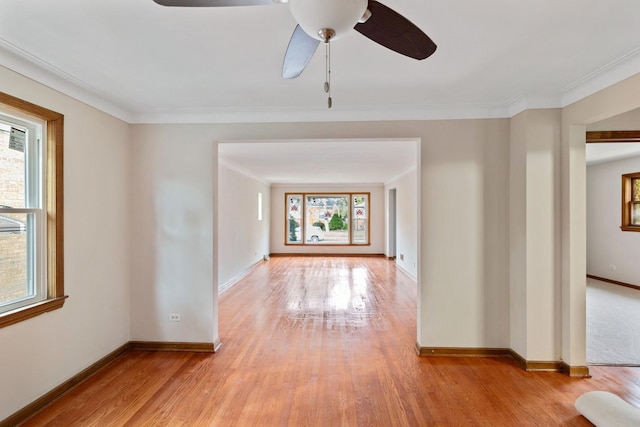 empty room with ornamental molding, light wood-type flooring, ceiling fan, and baseboards