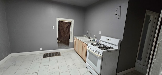 kitchen featuring white range with gas stovetop, baseboards, visible vents, marble finish floor, and a sink