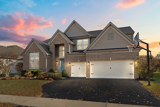 traditional home featuring aphalt driveway, a front yard, and brick siding