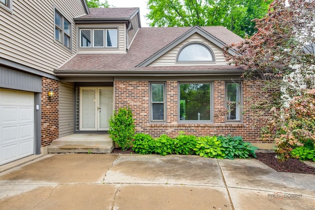 621 Raintree Rd, Buffalo Grove, IL 60089 - view of exterior entry with brick siding, a shingled roof, and a garage