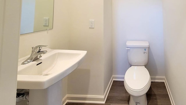 bathroom with a sink, toilet, baseboards, and wood finished floors