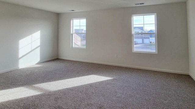 spare room featuring baseboards, visible vents, and carpet flooring