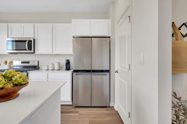 kitchen featuring white cabinets, light wood finished floors, stainless steel appliances, and light countertops