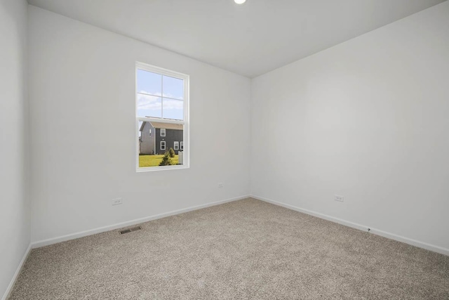 empty room featuring carpet, visible vents, and baseboards