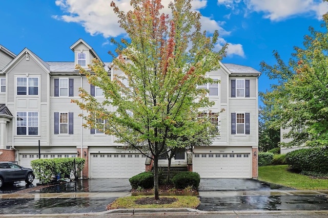 multi unit property featuring brick siding, driveway, and an attached garage