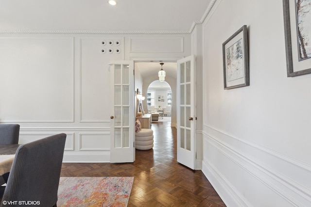 home office with arched walkways, french doors, and a decorative wall