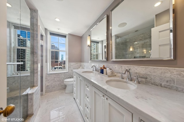 bathroom featuring toilet, marble finish floor, a tile shower, and a sink