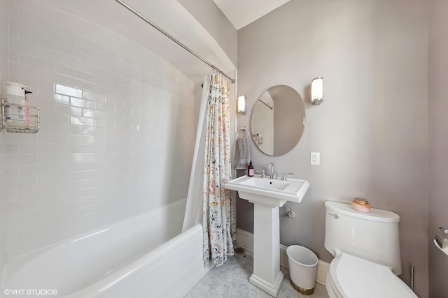 full bath with a sink, shower / bath combo with shower curtain, toilet, and baseboards