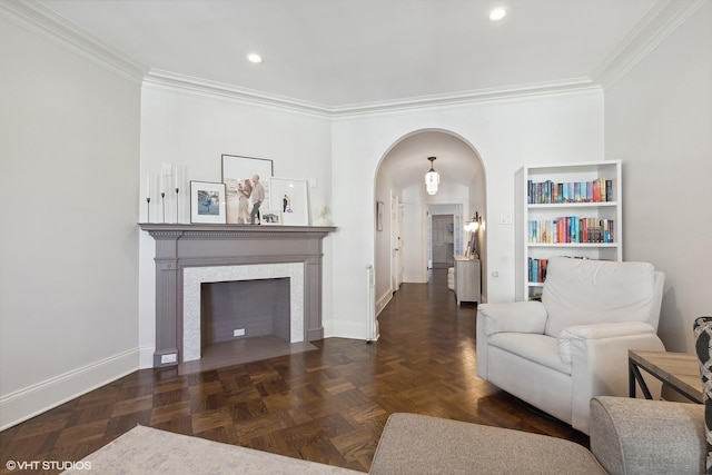 living room featuring arched walkways, recessed lighting, a fireplace with flush hearth, baseboards, and crown molding