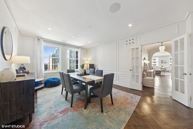 dining area with arched walkways, recessed lighting, a decorative wall, french doors, and ornamental molding