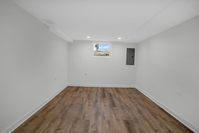 below grade area with recessed lighting, wood finished floors, electric panel, and baseboards