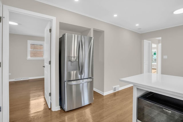 kitchen featuring wood finished floors, stainless steel fridge, visible vents, and baseboards